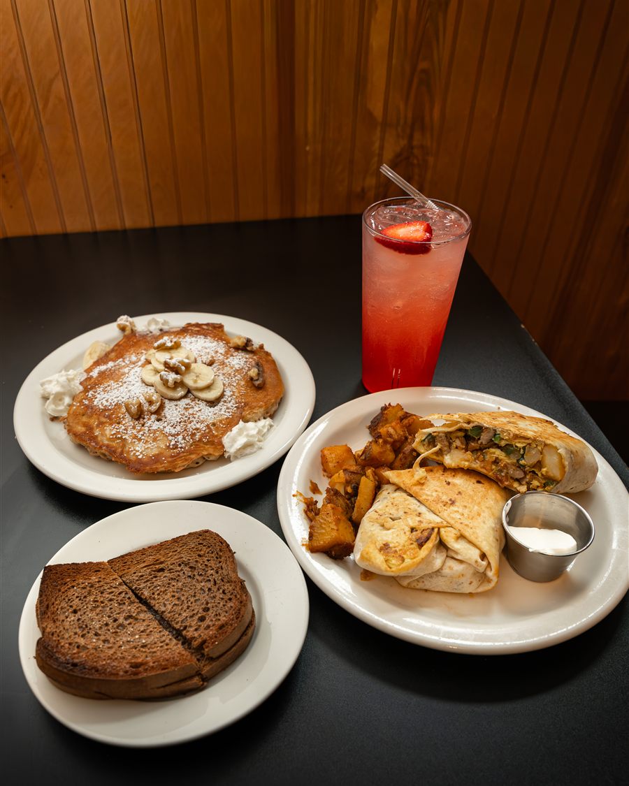 A table spread of pancakes, toast, a wrap and a fruit drink