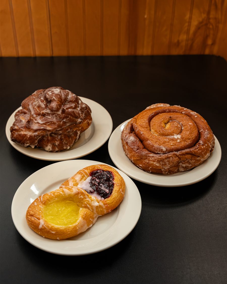 An apple fritter, a giant cinnamon roll and a glazed danish on diner plates